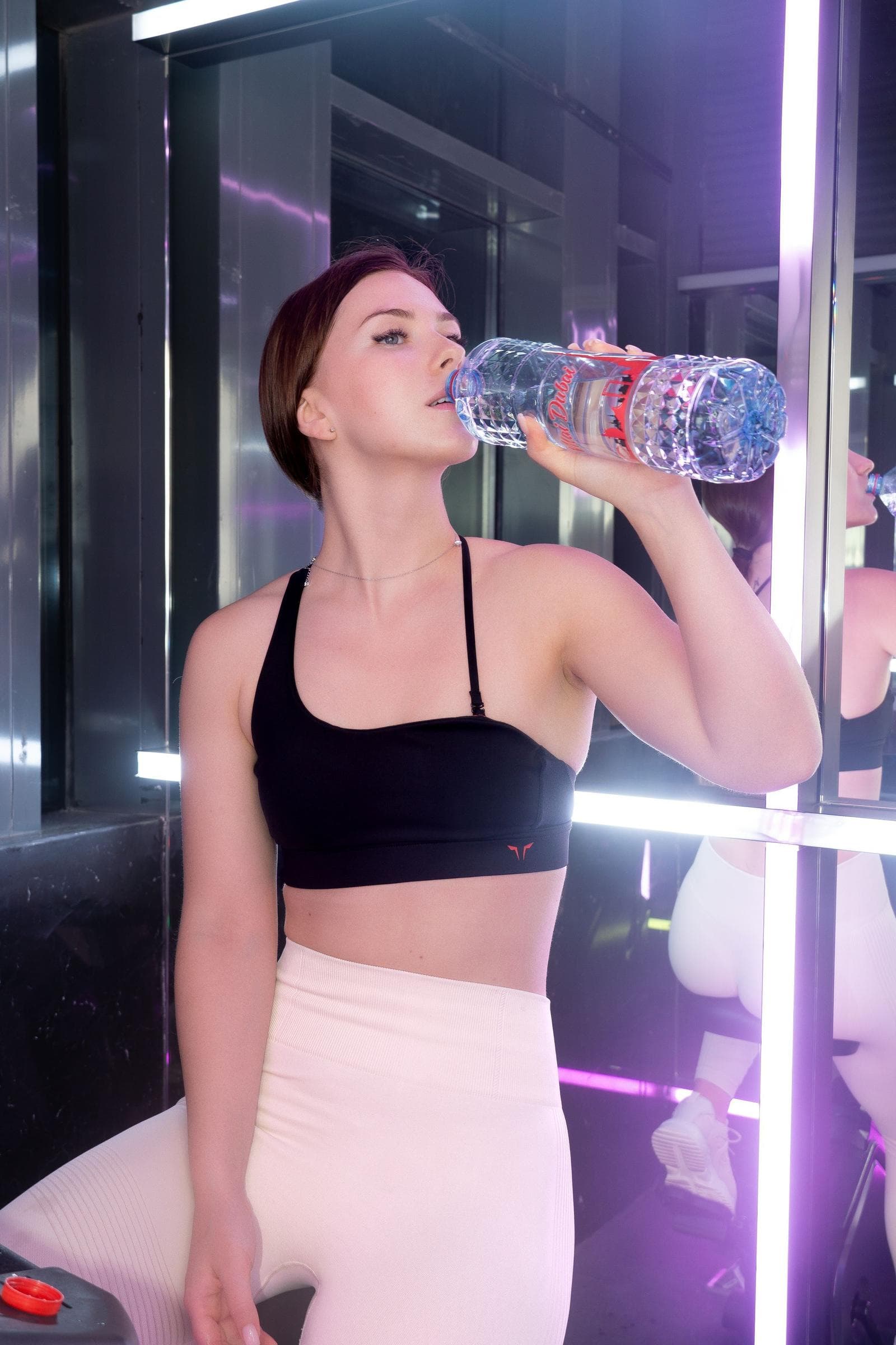 Athlete taking a water break in a gym with expressive lighting