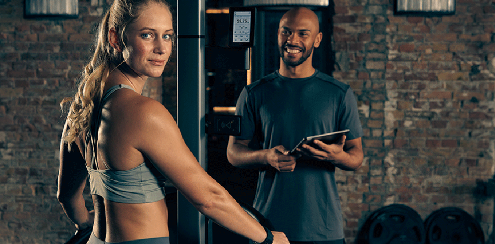 Trainer and athlete in a premium brick-wall gym environment
