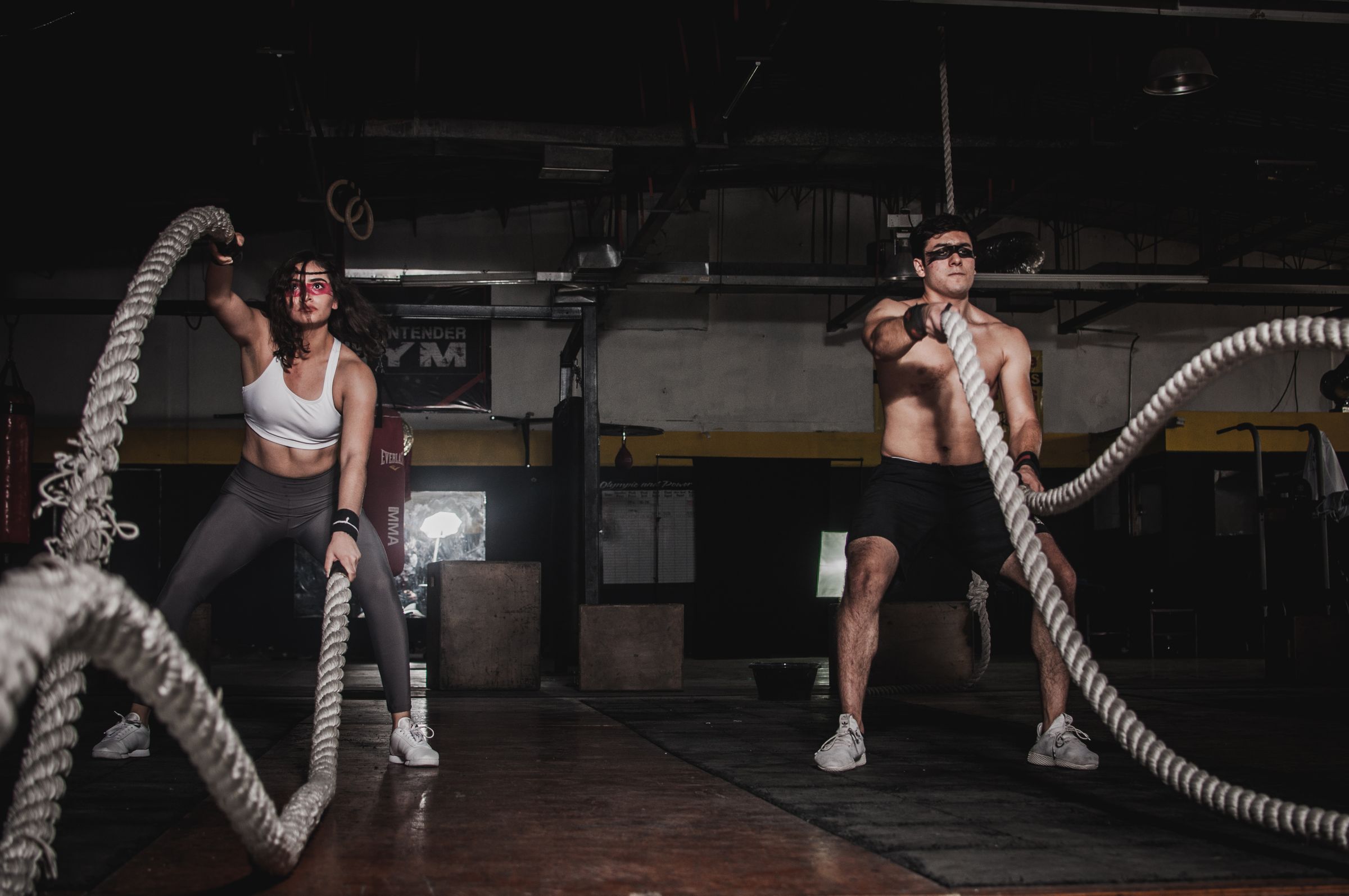 Two athletes training with battle ropes in a premium gym